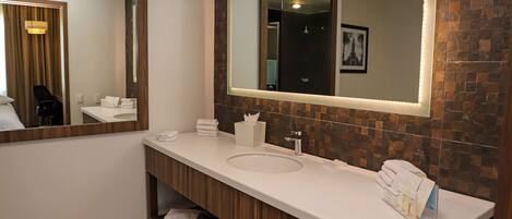 A modern bathroom with a large mirror, white sink, and wooden vanity.