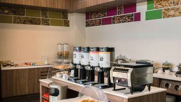A modern breakfast bar with coffee machines, a bread display, and a variety of condiments.