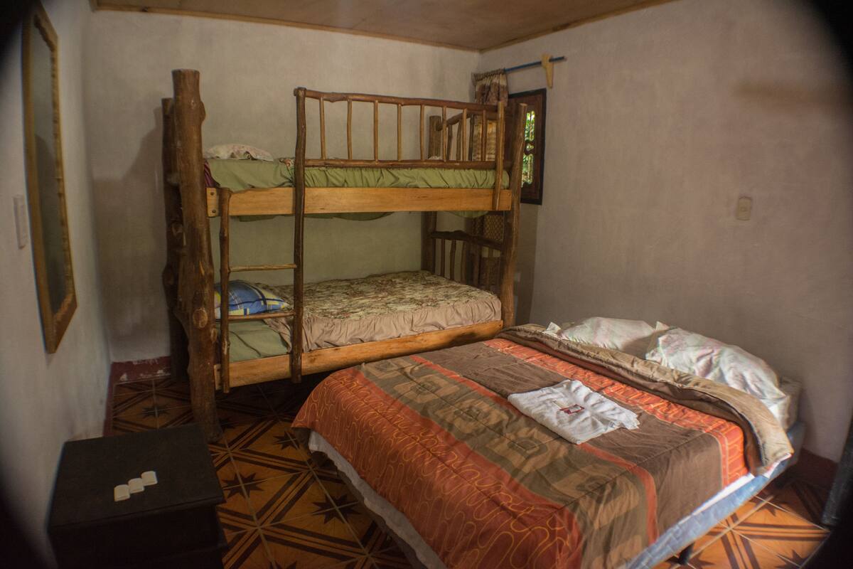 Una litera con una cama inferior y una individual, una mesita pequeña y un suelo estampado.