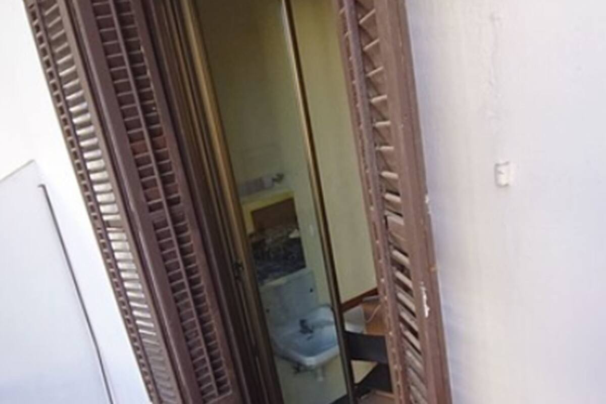 Ein Zimmer mit einer Schiebetür, einem sichtbaren Badezimmer mit Waschbecken und einem Fliesenboden.
