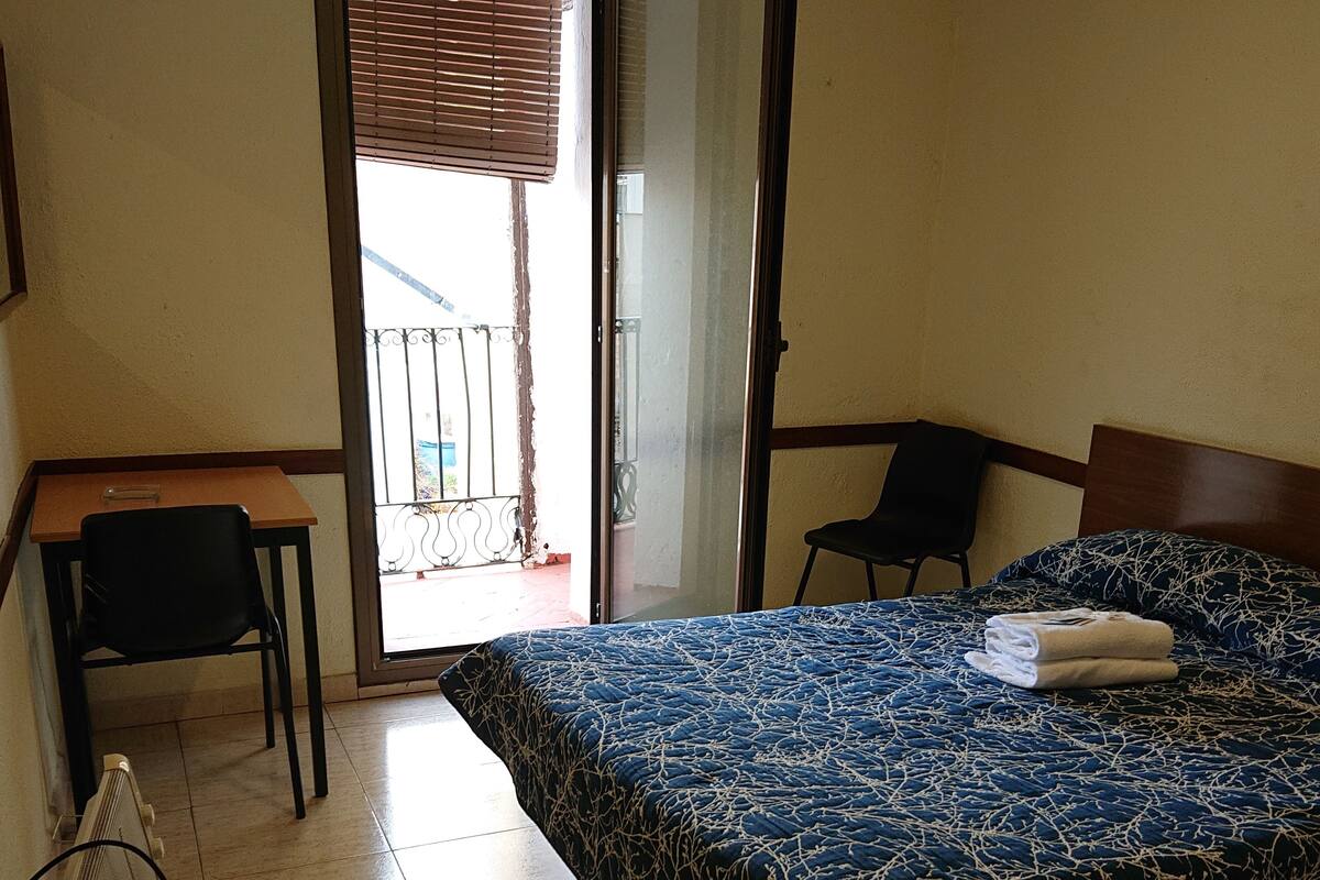 Ein Hotelzimmer mit Bett, Schreibtisch, Stuhl und Heizkörper.
