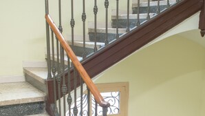 A staircase with a wooden handrail and metal balusters. - Hostal Nilo (Barcelona)