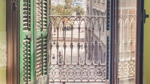 A balcony with a metal railing, a view of buildings, and a clear sky. - Hostal Nilo (Barcelona)