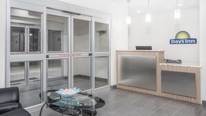 Una zona de recepción con un mostrador de cristal, una silla de cuero negro y una recepción.