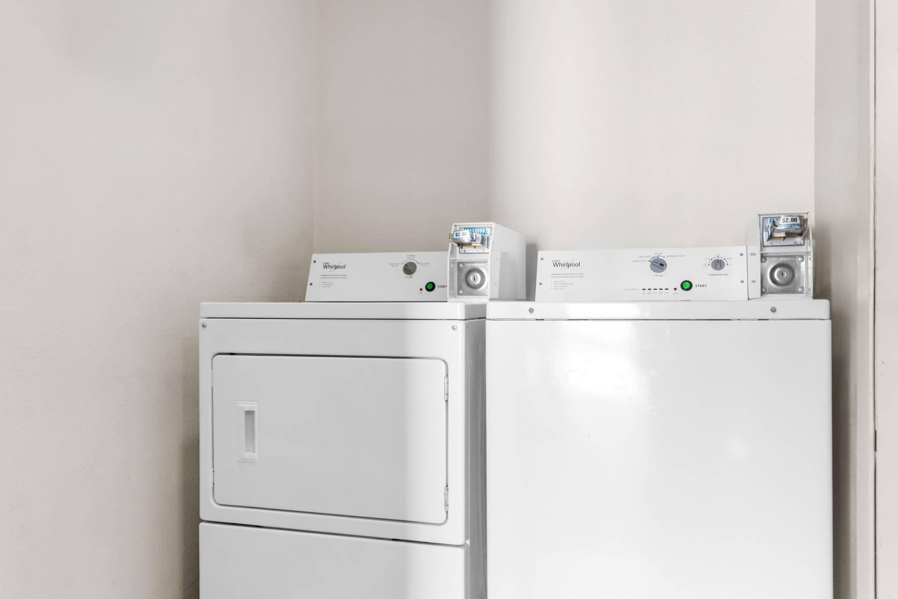 Dos lavadoras Whirlpool blancas una al lado de la otra en una habitación con paredes lisas.
