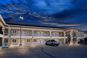 A multi-story hotel with a stone facade, balconies, and a parking area. - Econo Lodge (Bryan)