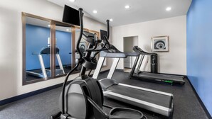Un gimnasio con cintas de correr, elíptica y bicicleta estática.