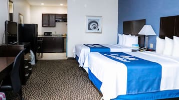 Una habitación de hotel con cama, escritorio, silla y kitchenette.