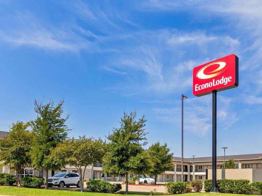 Un hôtel reconnaissable à son grand panneau « EconoLodge », entouré d’arbres et disposant d’un parking.