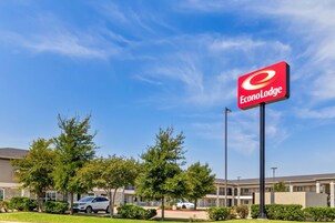 Un hotel con un letrero llamativo de EconoLodge, rodeado de árboles y un estacionamiento.