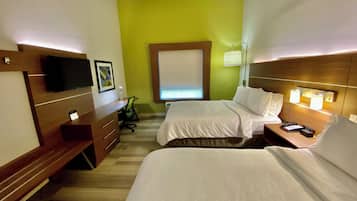 Una habitación de hotel con dos camas, un escritorio, una silla, un televisor y una ventana con persianas.