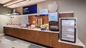 Un bar à petit-déjeuner moderne proposant une machine à café, des céréales et un choix de fruits.