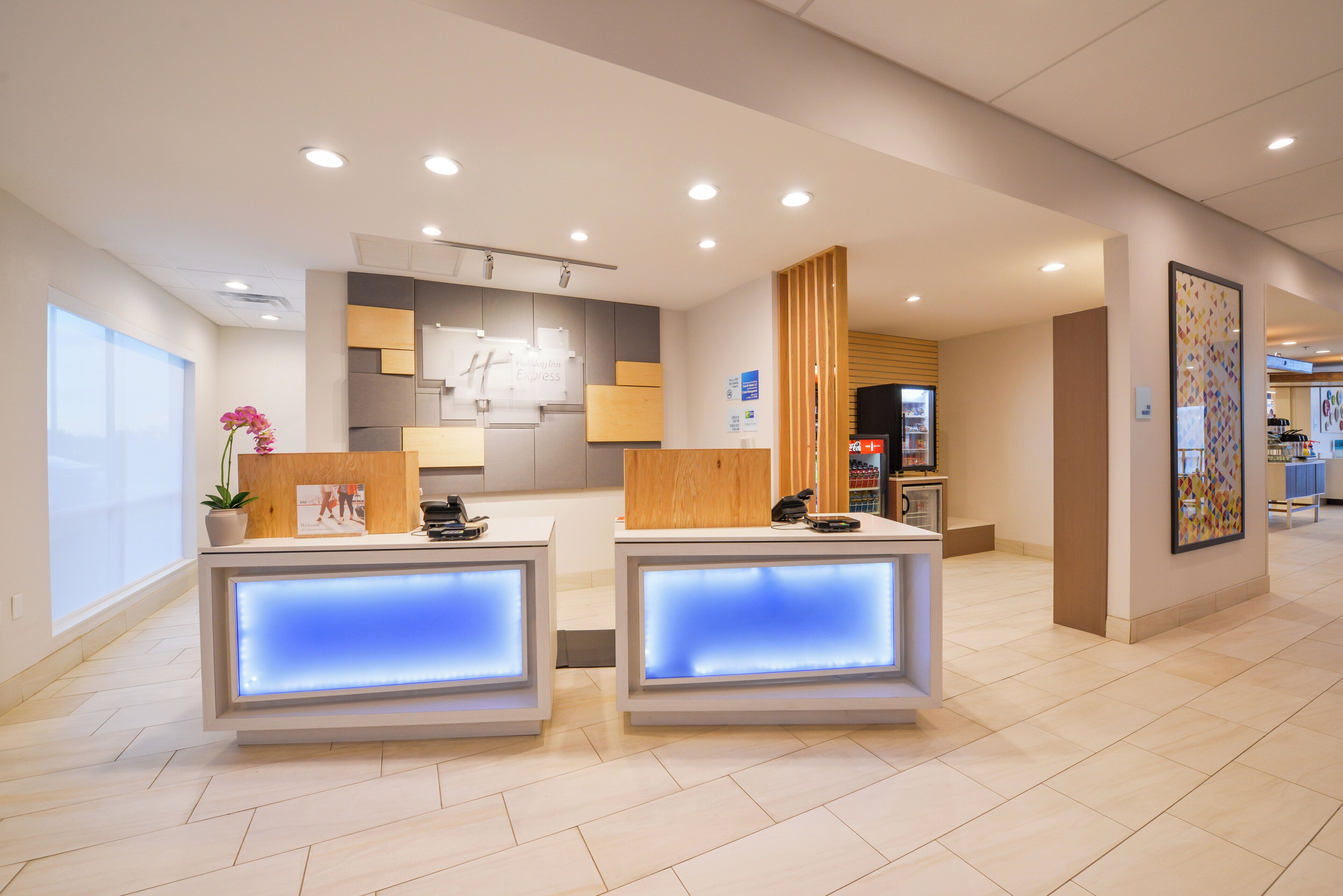 Un espace d’accueil d’hôtel comprenant deux comptoirs de réception, une grande fenêtre et un aménagement intérieur moderne.