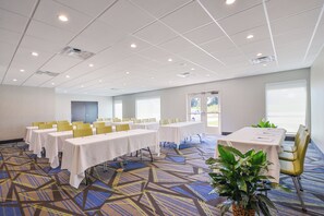 Uma sala de conferências com várias mesas, cadeiras e uma planta grande.