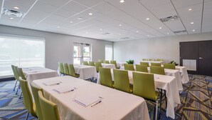 Ein Konferenzraum mit Tischen, Stühlen, großen Fenstern und einer Tür.