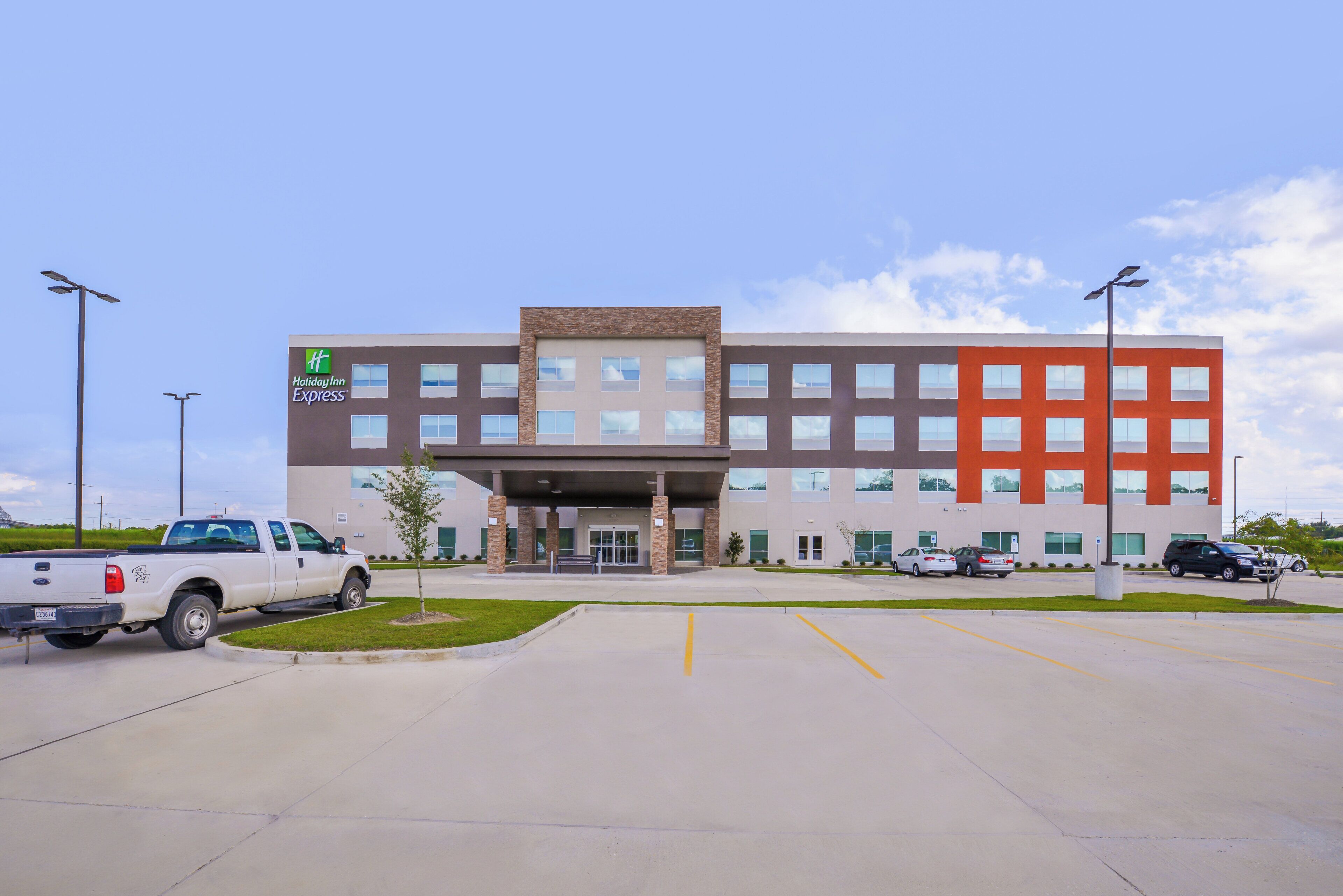 A Holiday Inn Express building with a parking lot, a white pickup truck, and a clear sky.