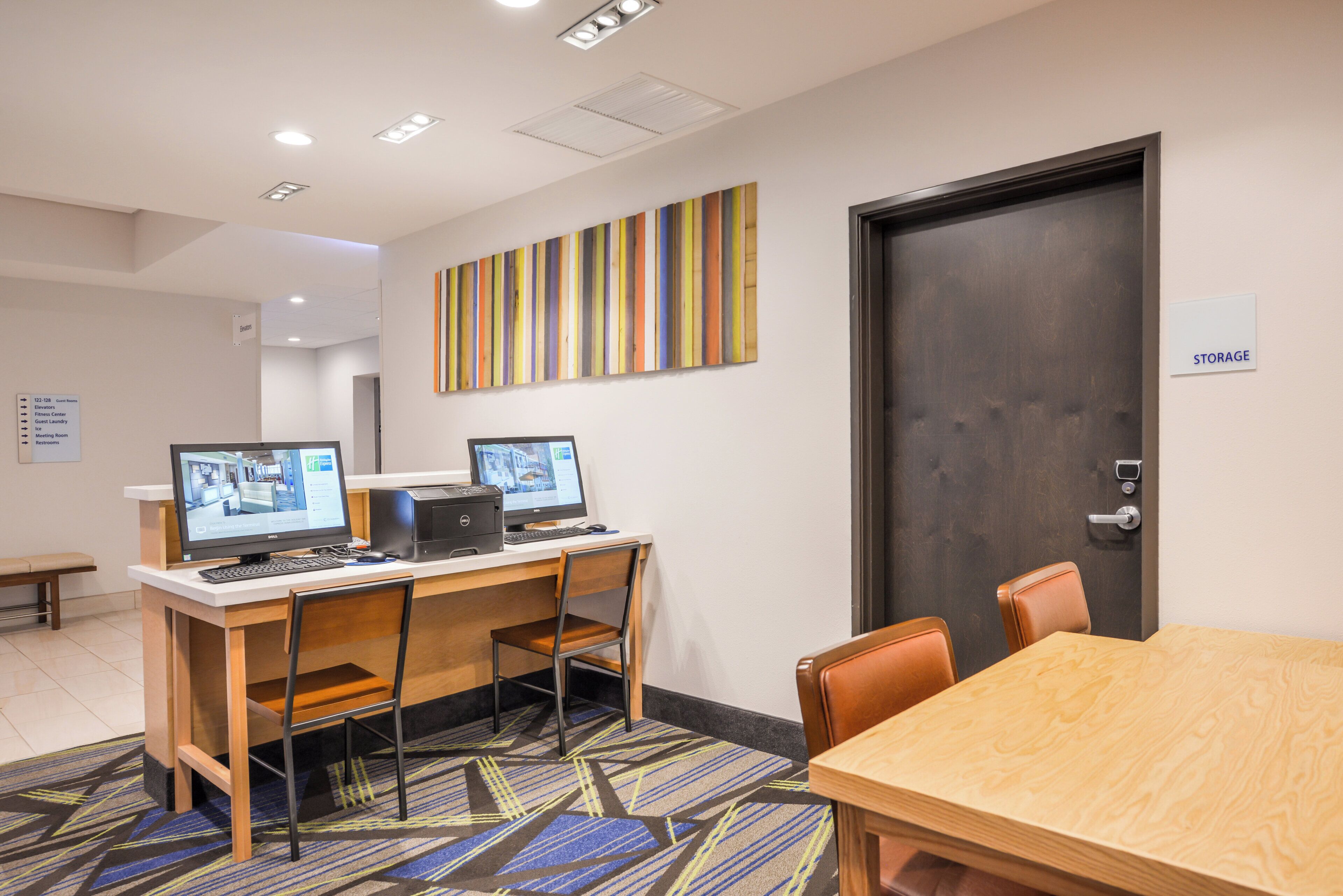 A conference room with two desks, chairs, a large wooden table, and a door labeled 'STORAGE'.