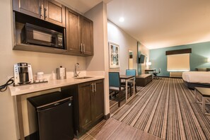A hotel room with a kitchenette, a dining area, and a bed. - Holiday Inn Express & Suites Houston - Hobby Airport Area by IHG (Houston)