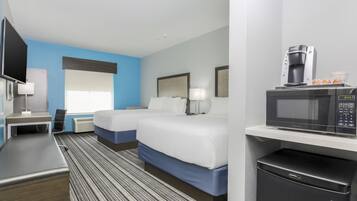 A hotel room with a bed, a desk, a television, a coffee maker, and a microwave.
