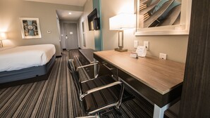 A hotel room with a bed, a desk with a chair, a TV, and a mirror. - Holiday Inn Express & Suites Houston - Hobby Airport Area by IHG (Houston)