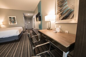 A hotel room with a bed, a desk with a chair, a TV, and a mirror. - Holiday Inn Express & Suites Houston - Hobby Airport Area by IHG (Houston)