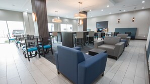A modern hotel lobby with seating areas, a reception desk, and a coffee bar. - Holiday Inn Express & Suites Houston - Hobby Airport Area by IHG (Houston)