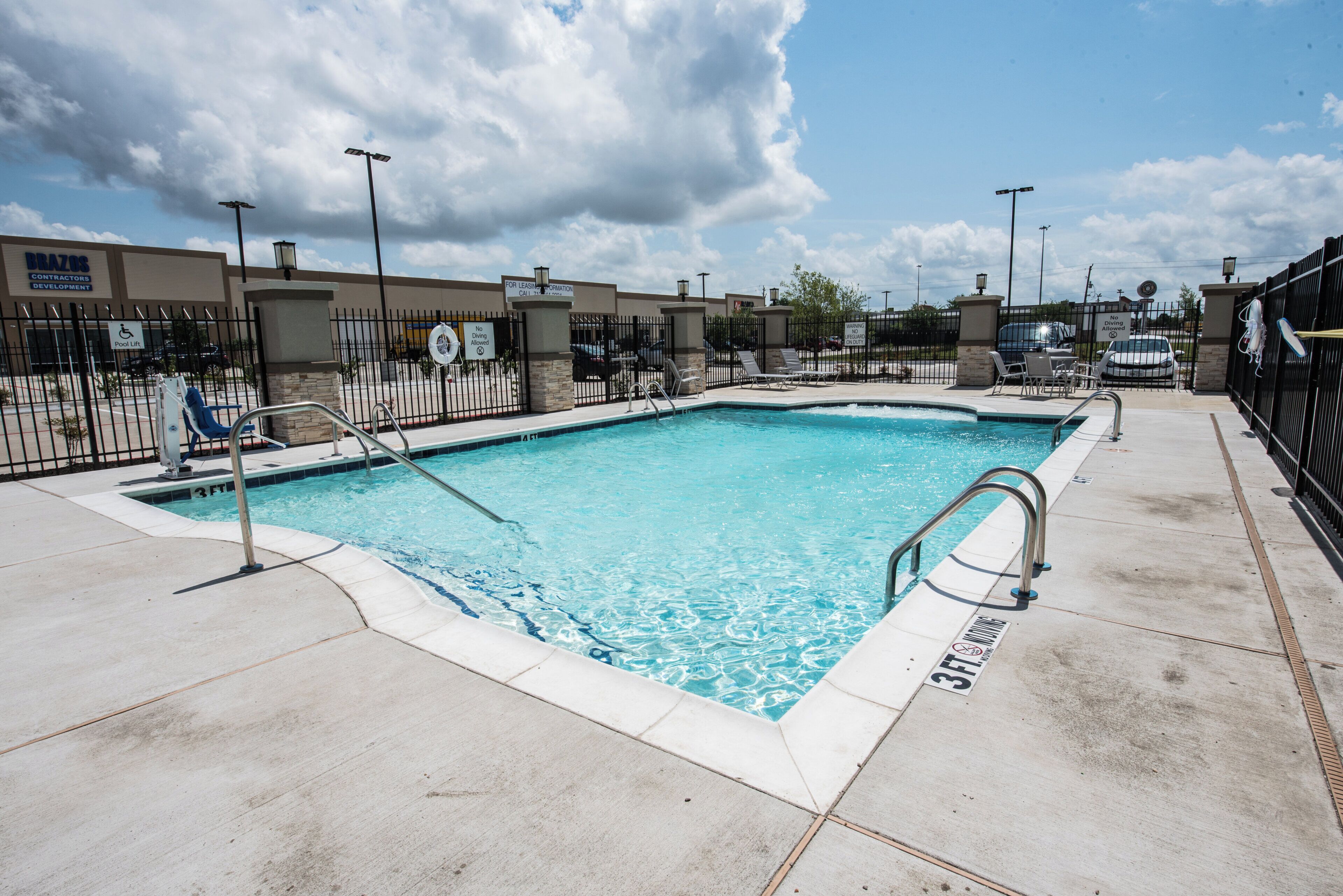Una piscina rectangular con un indicador de profundidad de 3 pies, rodeada por una cerca de metal negro y un letrero que dice 'No Diving'.