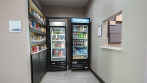 En gang med to automater til forfriskninger, et skilt med teksten "SUNDRIES" og et lille vindue med udsigt.