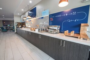 A modern breakfast area with a counter, seating, and directional signage. - Holiday Inn Express & Suites Houston - Hobby Airport Area by IHG (Houston)