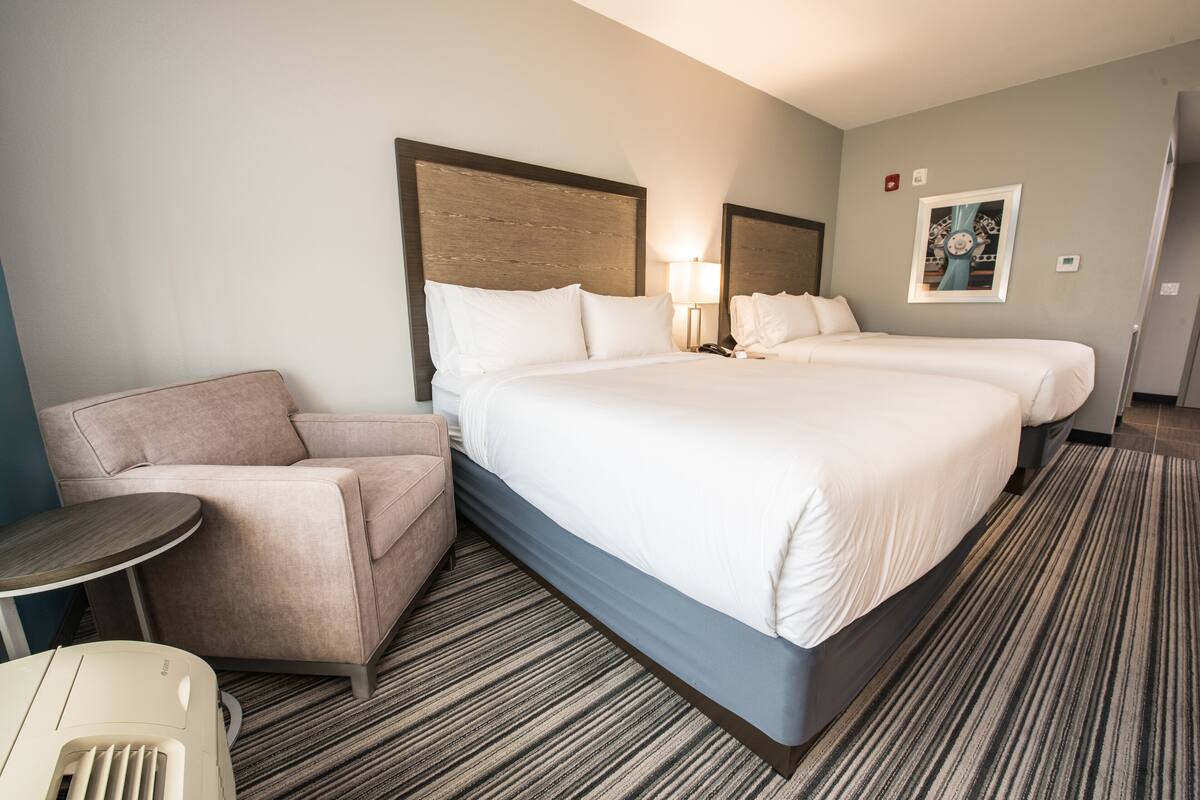A hotel room with a large bed, two bedside tables, a sofa, and a small round table.