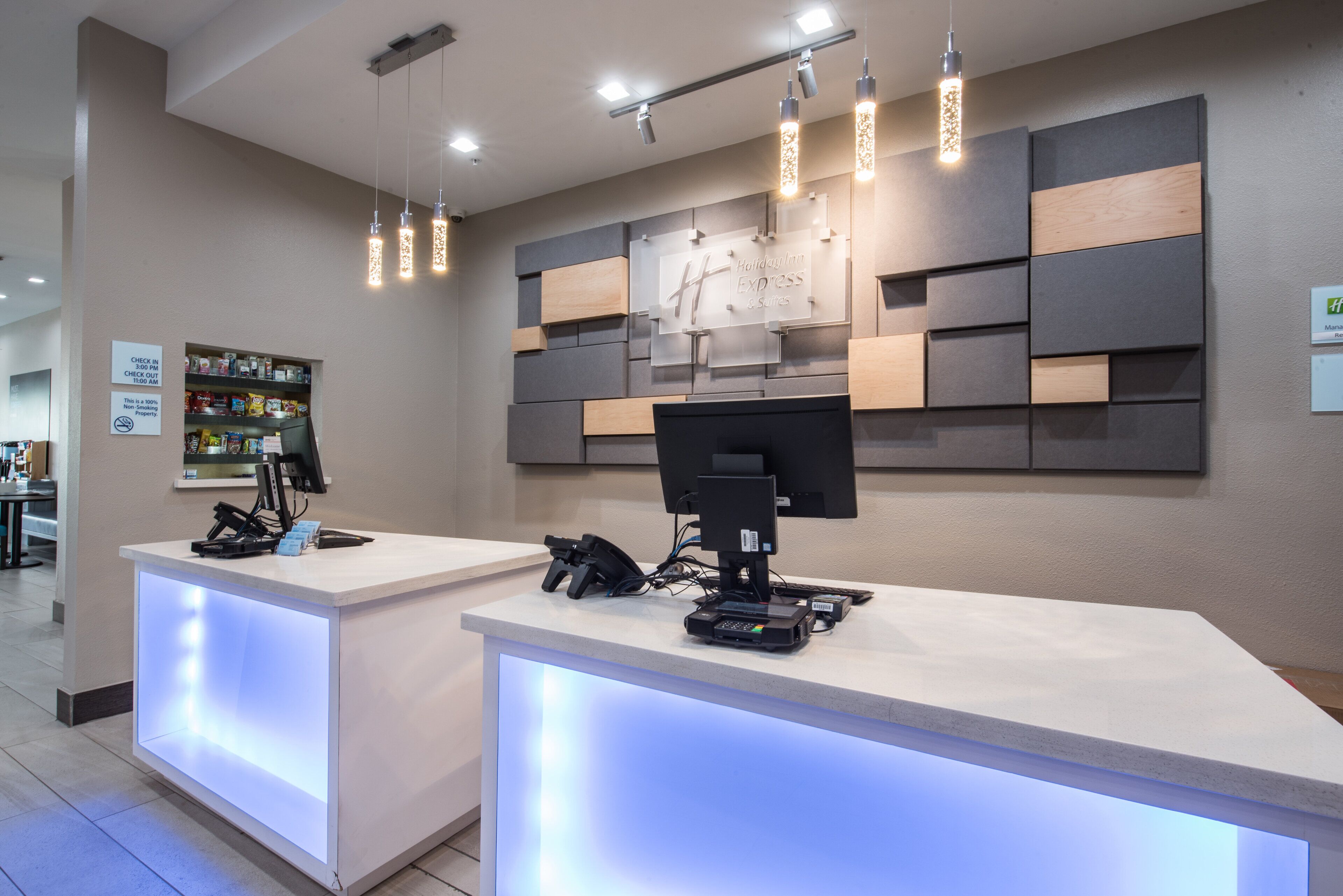 A hotel reception desk with a modern design, featuring a flat-screen monitor, a telephone, and a cash register.