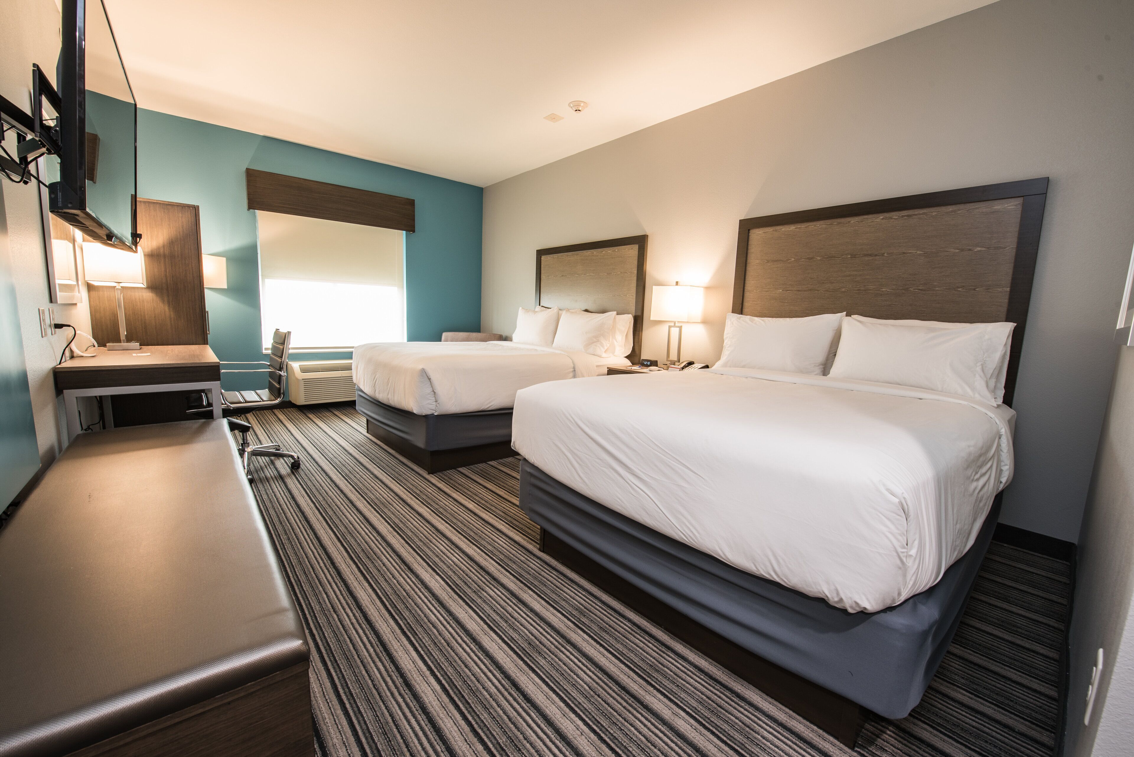 Ein Hotelzimmer mit zwei Betten, einem Schreibtisch, einem Stuhl und einem Fernseher.