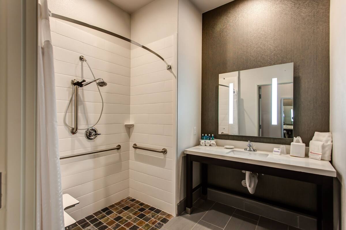 A modern bathroom with a shower, a vanity with a mirror, and a toilet.