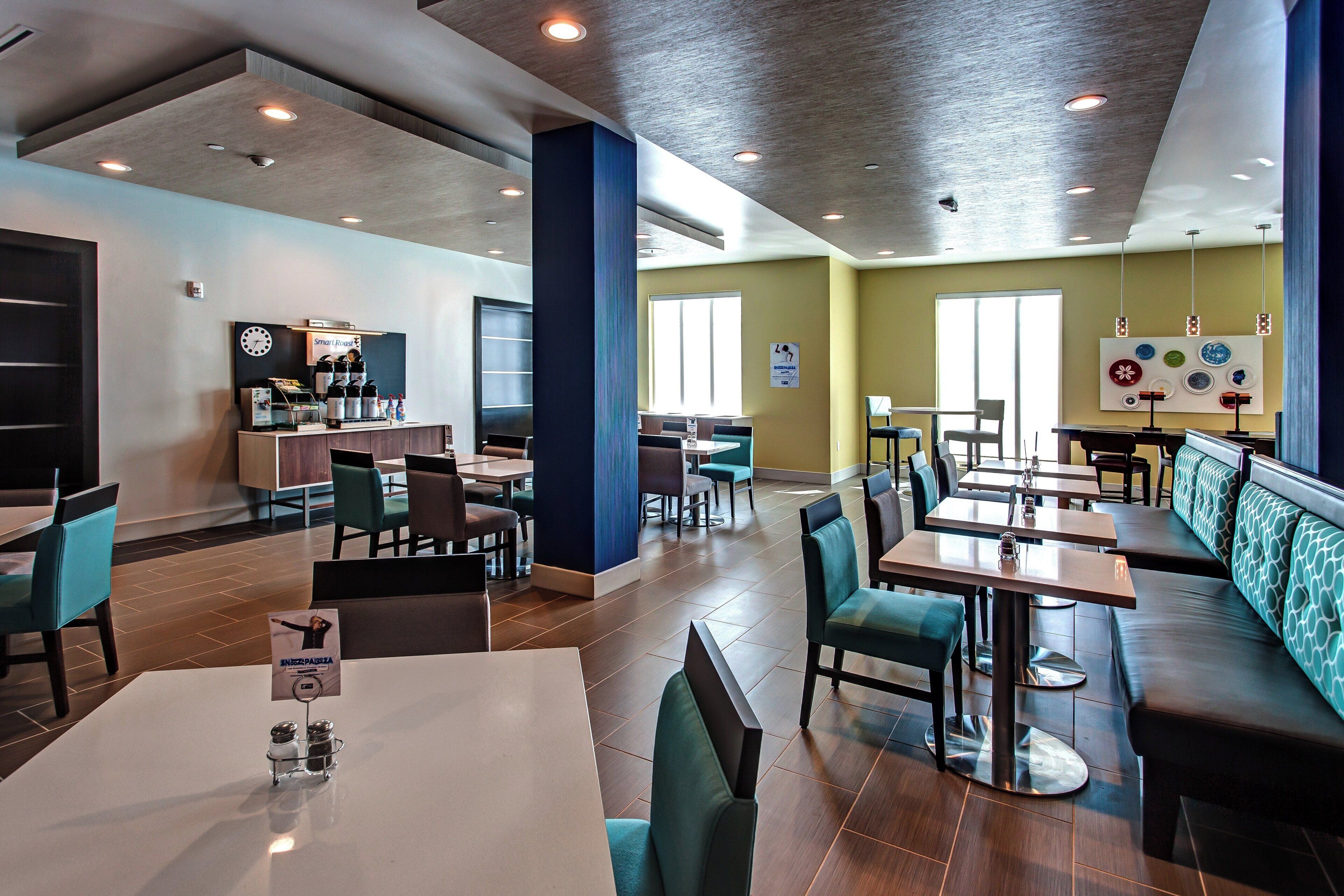 A modern restaurant with booths and tables, a clock on the wall, and a menu stand.