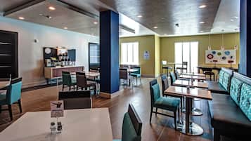 A modern restaurant with booths and tables, a clock on the wall, and a menu stand.