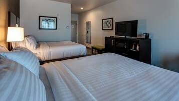 A hotel room with two beds, a television, a microwave, and a small table.