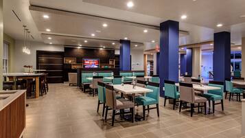 A modern restaurant with booths and tables, a TV screen displaying a news program, and a variety of seating options.