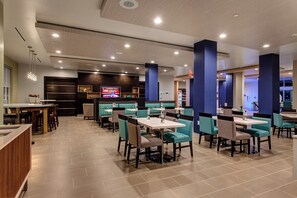 En moderne restaurant med både båse og borde, et tv der viser nyheder, og forskellige siddepladser.