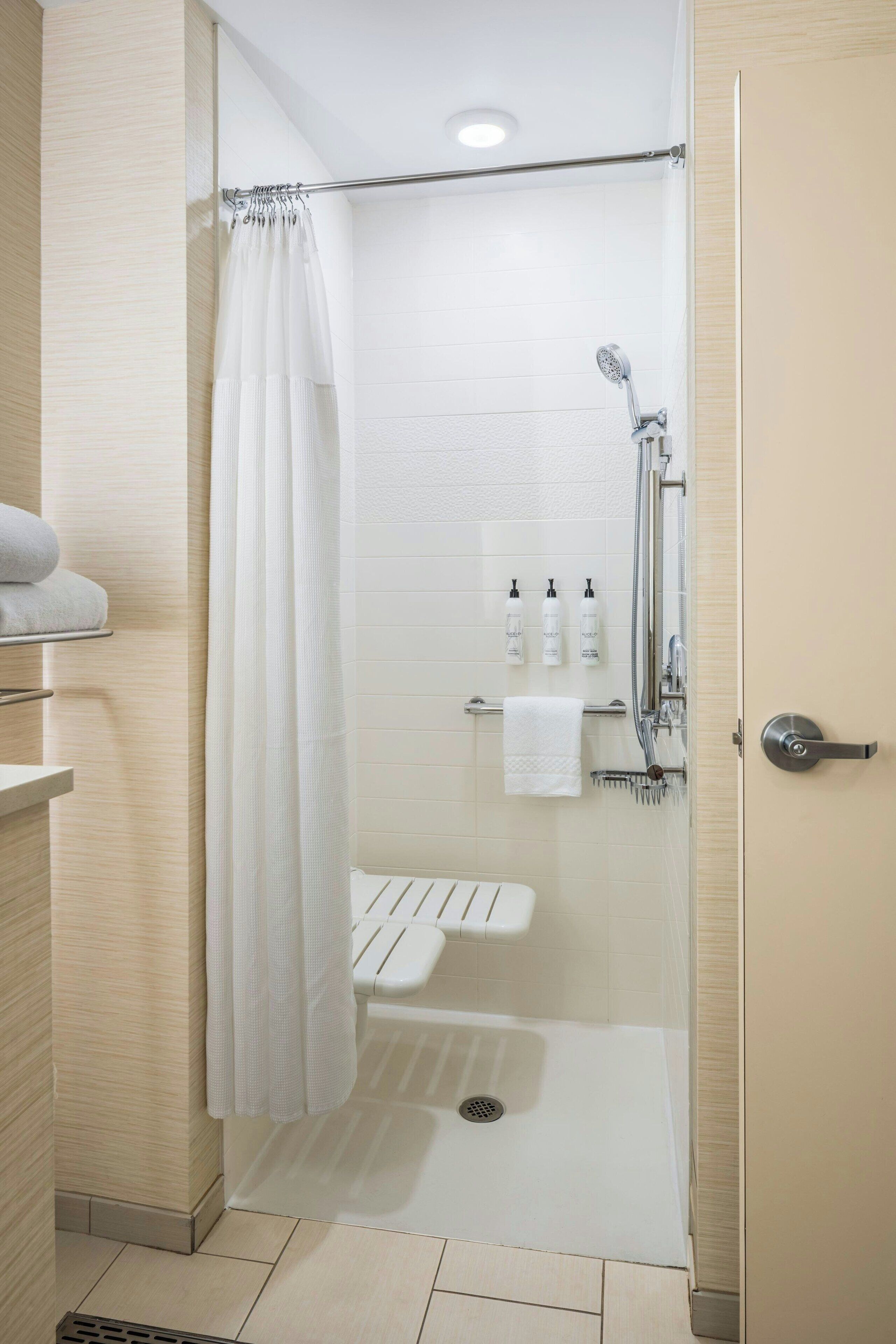 A modern shower area with a glass door, a handheld showerhead, and a white towel rack.