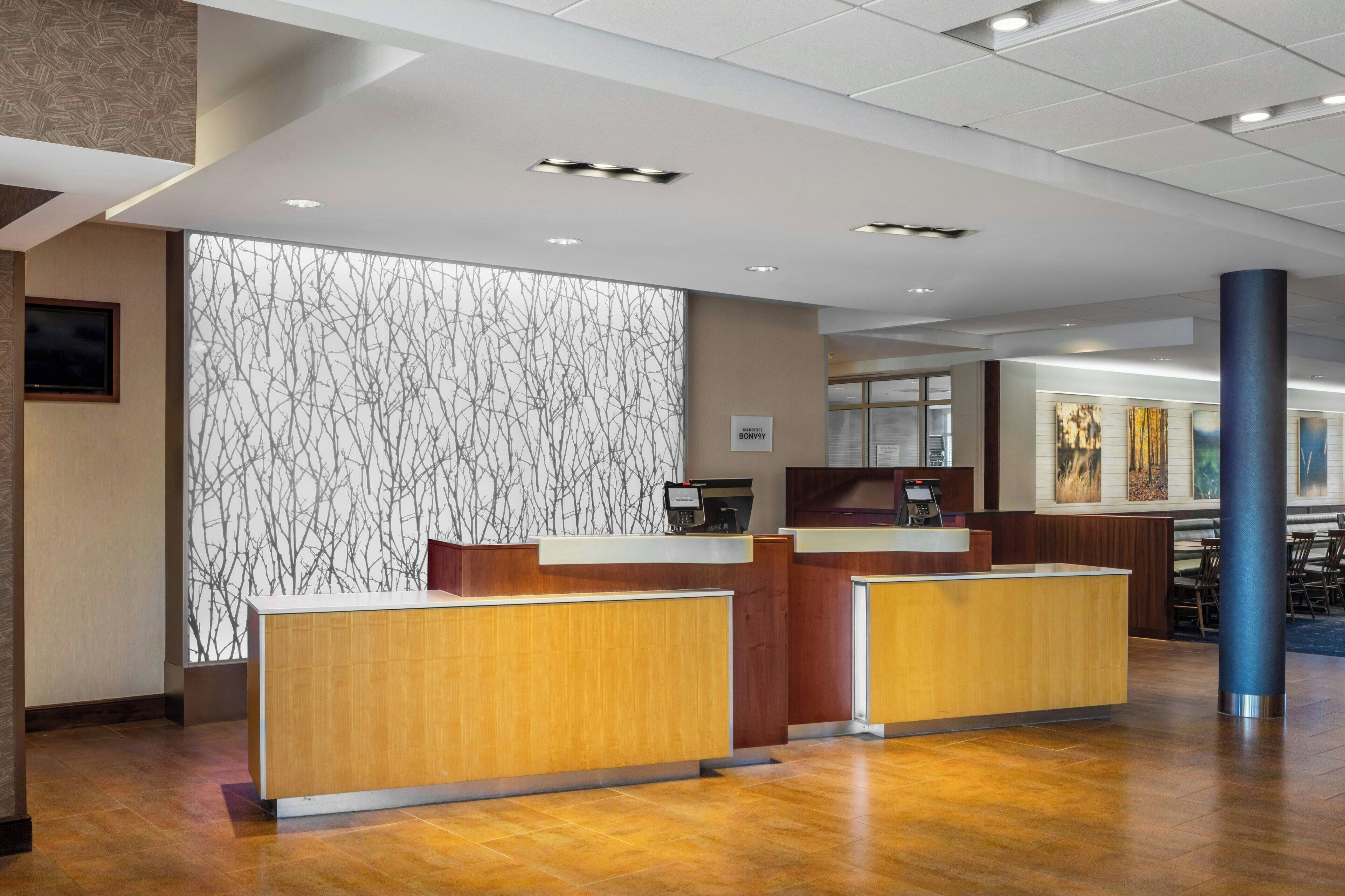 Un espace d’accueil avec des comptoirs de réception en bois, un mur décoré de motifs et une grande colonne.