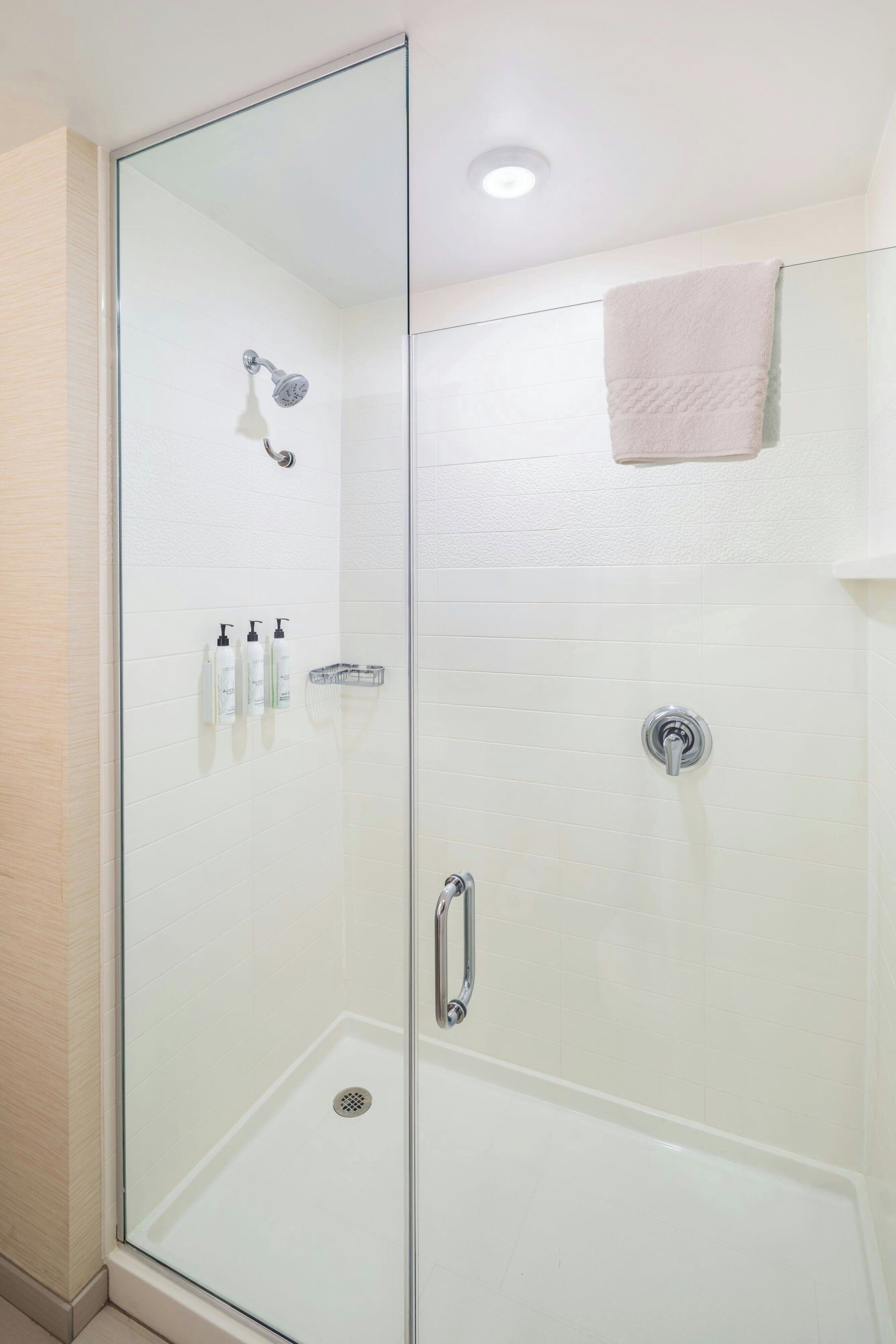 A glass-enclosed shower area with a handheld showerhead, a handheld showerhead, and a handheld showerhead.