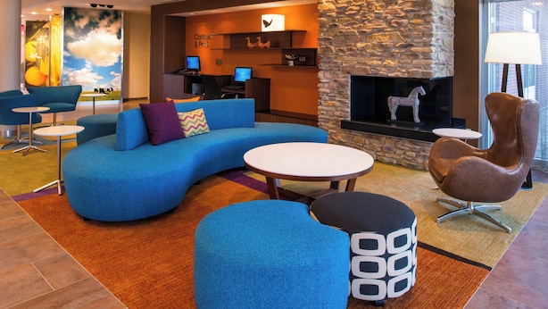 Ein moderner Lounge-Bereich mit einem gewölbten, blauen Sofa, einem braunen Ledersessel und einem Steinkamin.