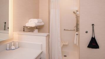 Ein modernes Badezimmer mit Dusche, Waschbecken und Pflegeprodukten sowie einem Handtuchhalter.