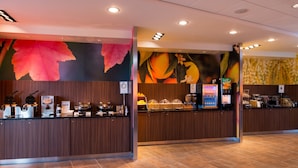 Ein Hotel-Empfangsbereich mit Holztresen, einer Wandmalerei zum Thema Früchte und einer Selbstbedienungs-Kiosk.