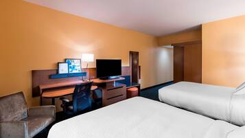 Een hotelkamer met twee bedden, een bureau met een televisie, een stoel en een kledingkast.