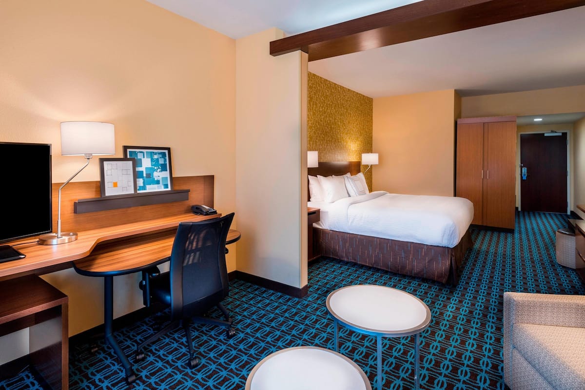 A hotel room with a bed, desk, chair, and a small table.