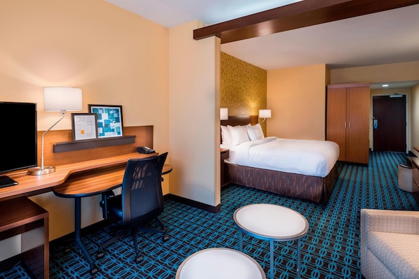 Una habitación de hotel con cama, escritorio, silla y una mesita.