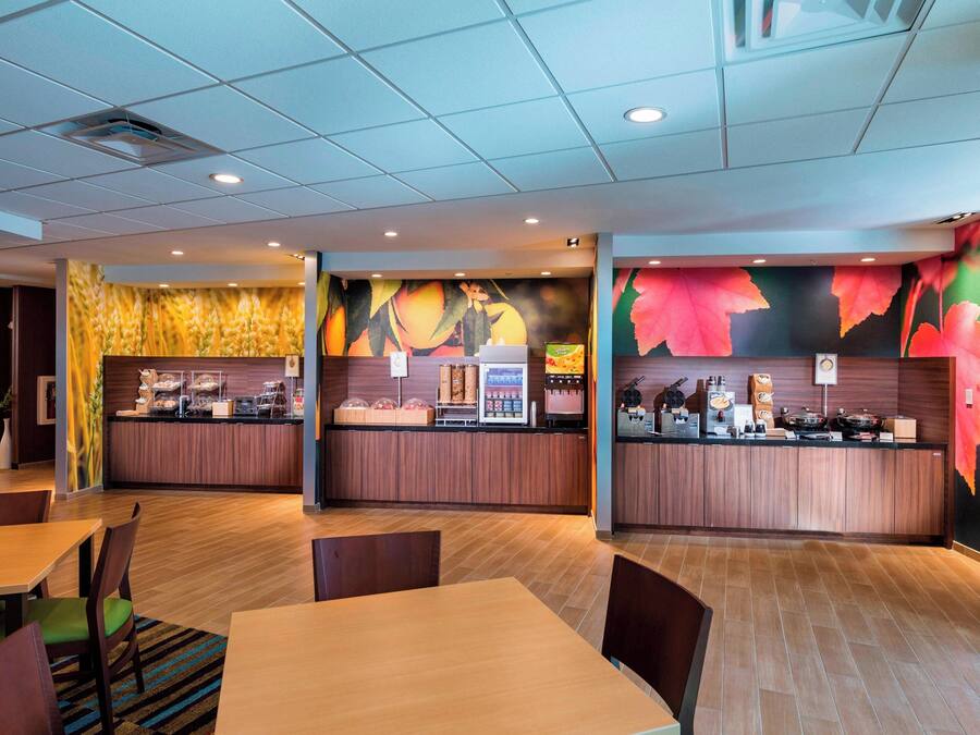 A modern restaurant with wooden flooring, a counter with food items, and a seating area with tables and chairs.