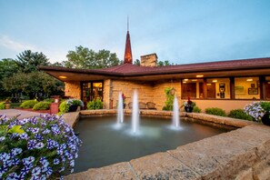 A building with a stone facade, a pointed roof, and a fountain in the courtyard.