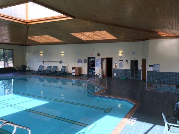 An indoor swimming pool with clear lanes, a changing room, and a sunlit ceiling.